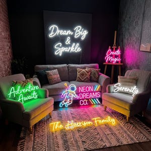 May include: A room with several neon signs. The signs include the phrases "Dream Big & Sparkle", "Create Magic", "Adventure Awaits", "Serenity", "Neon Dreams Co.", and "The Harrison Family". The signs are in various colors, including white, pink, green, and yellow.