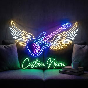 May include: A neon sign featuring a guitar with angel wings, illuminated in blue, purple, yellow, and white. The words "Custom Neon" are written in green neon below the guitar. The sign is displayed on a dark background.