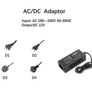May include: A black AC/DC adapter with a power cord and four different plug types. The adapter has the text "AC/DC ADAPTER" printed on it. The text "Input: AC 100-240V 50-60HZ Outpu:DC 12V" is printed above the adapter.