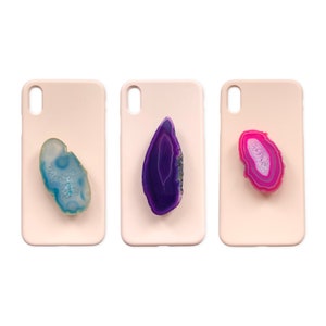 Könnte beinhalten: Drei rosa Handyhüllen mit verschiedenen farbigen Achat-Scheiben, die auf der Rückseite befestigt sind. Die Achat-Scheiben sind blau, lila und rosa.