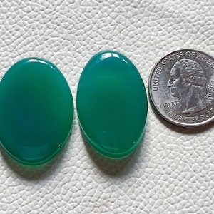 Può includere: Due cabochon ovali in agata verde, ciascuno delle dimensioni di una moneta da 25 centesimi di dollaro americano.