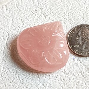 Può includere: Un cabochon di quarzo rosa intagliato con un motivo floreale. La pietra è circa delle dimensioni di una moneta da 25 centesimi di dollaro americano.
