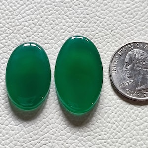 Può includere: Due cabochon ovali in agata verde, il più grande è leggermente più grande di una moneta da 25 centesimi di dollaro americano.