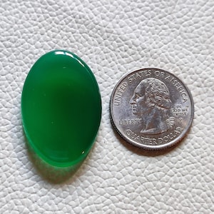 Può includere: Un cabochon di pietra preziosa verde ovale e liscio. La pietra preziosa è circa delle dimensioni di una moneta da 25 centesimi di dollaro americano.