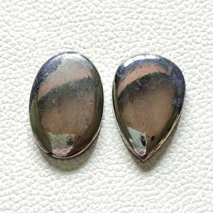 Può includere: Due cabochon di pirite a forma di pera, uno ovale e uno a forma di lacrima, con un colore argento metallizzato e marrone.