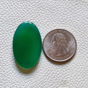 Può includere: Un cabochon di agata verde liscio di forma ovale, circa delle dimensioni di una moneta da 25 centesimi di dollaro americano.