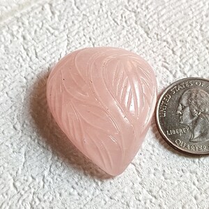 Può includere: Un ciondolo in quarzo rosa a forma di cuore intagliato con un motivo a foglie. Il ciondolo è circa delle dimensioni di una moneta da 25 centesimi di dollaro americano.