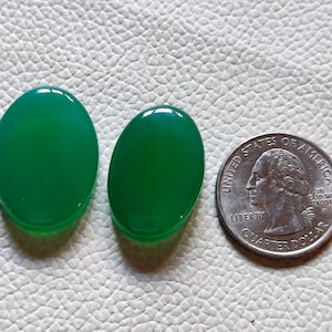 Può includere: Due pietre preziose verdi di forma ovale, ciascuna delle dimensioni di una moneta da 25 centesimi di dollaro americano.