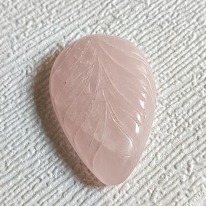 Può includere: Un ciondolo in quarzo rosa di colore rosa pallido, a forma di foglia e intagliato.