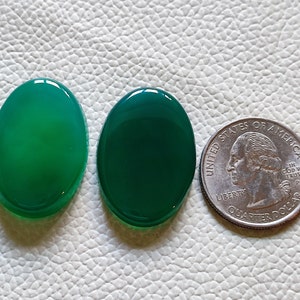 Può includere: Due cabochon ovali in agata verde, ciascuno delle dimensioni di una moneta da 25 centesimi di dollaro americano.