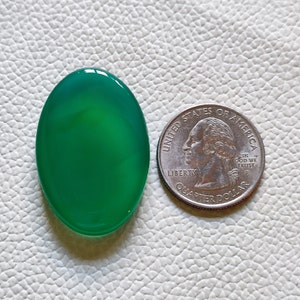 Può includere: Un cabochon di agata ovale di colore verde, circa delle dimensioni di una moneta da 25 centesimi di dollaro americano.
