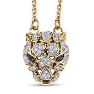 Puede incluir: Un collar con colgante dorado que representa una cabeza de pantera estilizada. La cara de la pantera está adornada con numerosos diamantes pequeños y brillantes y dos piedras preciosas de color verde oscuro para los ojos. La cadena del collar también es dorada.