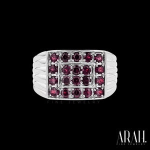 May include: A silver ring with a square face, set with numerous small, round, deep red gemstones. The ring has a ribbed design on the sides and the words "FINE JEWELRY" are printed on the bottom.