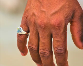 May include: A silver ring with a large oval opal gemstone. The opal has a rainbow of colors, including green, blue, and purple.