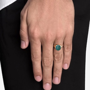 May include: A gold signet ring with a green oval gemstone.