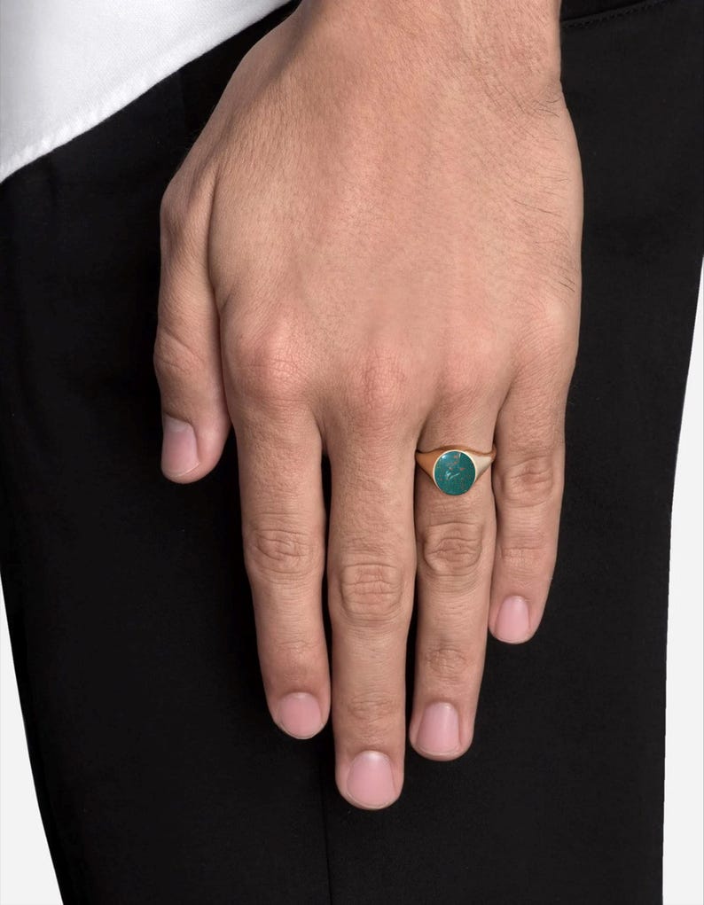 May include: A gold signet ring with a green oval gemstone.