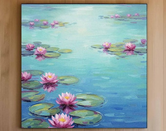 May include: A large framed painting depicting pink water lilies and green lily pads on a blue-green water surface. The artwork is displayed above a white sofa in a modern living room setting, with a wooden coffee table.