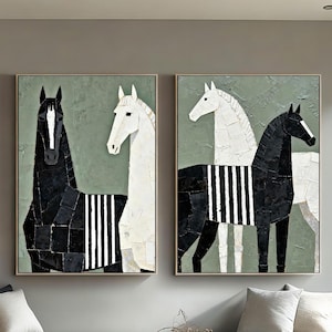 May include: Two framed abstract art pieces featuring horses. One painting shows a black horse with white stripes, the other a white horse with black stripes. Both have a green background and gold frames. The artwork is displayed above a modern sofa.