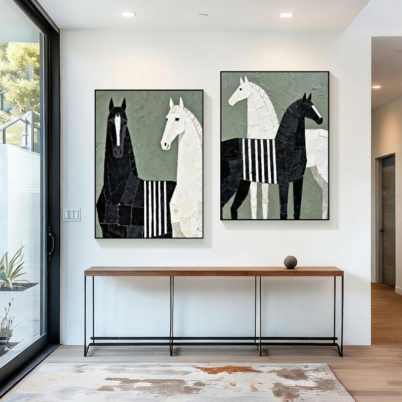 May include: Two framed abstract horse paintings. One features a black horse and a white horse with a striped pattern. The other painting has a white horse and a black horse with a striped pattern. The paintings are displayed above a wooden console table.