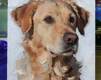 May include: Oil painting of a golden retriever dog with brown eyes and a pink nose. The dog's fur is painted in shades of tan and brown, with visible brushstrokes. The painting is displayed on a small wooden easel.