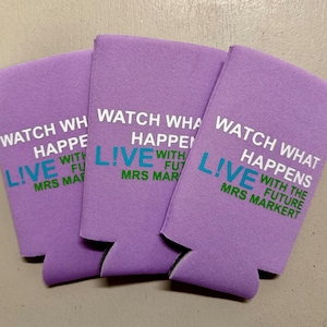 May include: Three lavender-colored can coolers with the text "WATCH WHAT HAPPENS LIVE WITH THE FUTURE MRS MARKERT" printed in white, teal, and green. The coolers are made of a foam-like material.
