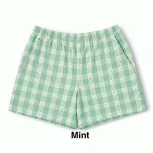 K&ouml;nnte beinhalten: Minzgr&uuml;ne Shorts mit wei&szlig;em Karomuster. Die Shorts verf&uuml;gen &uuml;ber einen elastischen Bund, zwei Seitentaschen und einen geraden Schnitt. Das Wort Mint ist in schwarzer Schrift unter dem Kleidungsst&uuml;ck aufgedruckt und gibt die Farbe an.