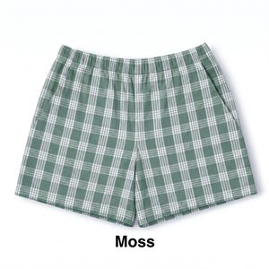 K&ouml;nnte beinhalten: Moosgr&uuml;ne Shorts mit wei&szlig;em Karomuster, elastischem Bund und Seitentaschen. Der Stoff zeigt ein durchgehendes, gleichm&auml;&szlig;iges Gitterdesign, wobei das Wort Moss in schwarzer Schrift unterhalb der Shorts abgedruckt ist.