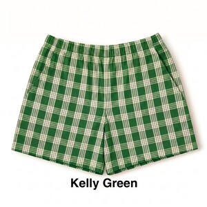 K&ouml;nnte beinhalten: Kellygr&uuml;ne Shorts mit einem wei&szlig;en und dunkelgr&uuml;nen Karomuster. Die Shorts verf&uuml;gen &uuml;ber einen elastischen Bund und zwei Seitentaschen. Der Text "Kelly Green" ist unter dem Kleidungsst&uuml;ck in Schwarz gedruckt und benennt die Farbe.
