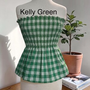 Peut inclure: Un haut tube sans bretelles vert Kelly avec un motif &agrave; carreaux blancs. Le v&ecirc;tement pr&eacute;sente un corsage smock&eacute; et &eacute;lastique avec un bord sup&eacute;rieur volant&eacute; et un ourlet &agrave; basque &eacute;vas&eacute;. Le texte Kelly Green est imprim&eacute; au-dessus du haut.