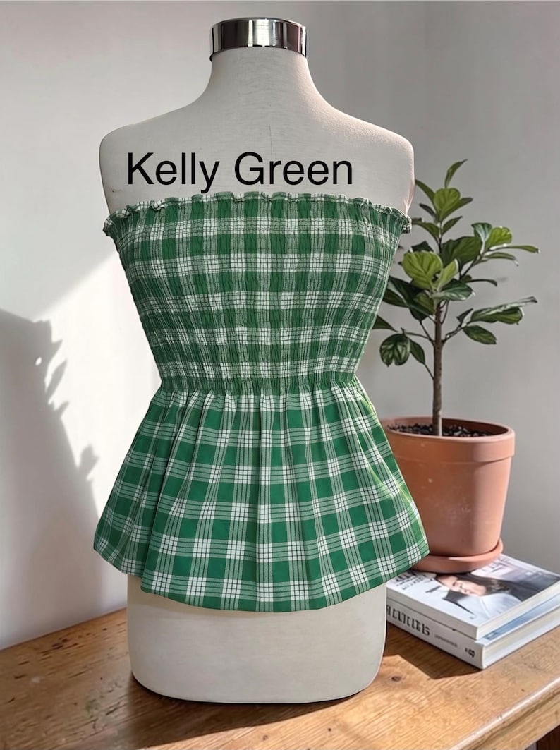 Peut inclure: Un haut tube sans bretelles vert Kelly avec un motif &agrave; carreaux blancs. Le v&ecirc;tement pr&eacute;sente un corsage smock&eacute; et &eacute;lastique avec un bord sup&eacute;rieur volant&eacute; et un ourlet &agrave; basque &eacute;vas&eacute;. Le texte Kelly Green est imprim&eacute; au-dessus du haut.