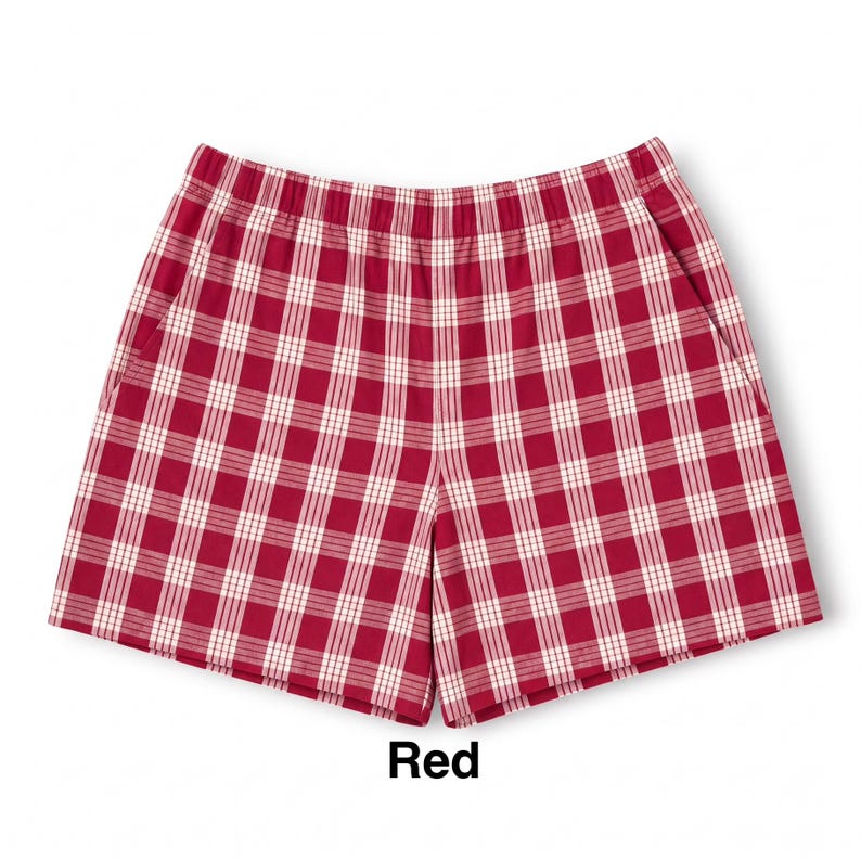 K&ouml;nnte beinhalten: Eine kurze Hose mit einem rot-wei&szlig;en Karomuster und einem Gitterdesign. Die Hose hat einen elastischen Bund und zwei Seitentaschen. Das Wort Red ist in schwarzer Schrift unter dem Kleidungsst&uuml;ck auf wei&szlig;em Hintergrund gedruckt.
