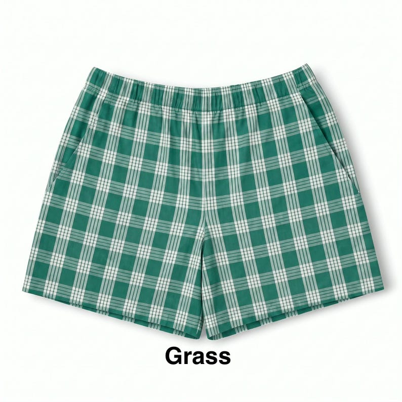 K&ouml;nnte beinhalten: Gr&uuml;n-wei&szlig; karierte Shorts mit elastischem Bund und zwei Seitentaschen. Der Stoff zeigt ein durchgehendes Karomuster. Unter den Shorts ist das Wort Grass in schwarzer Schrift aufgedruckt.