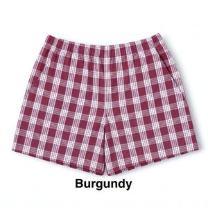 K&ouml;nnte beinhalten: Burgunderrote Shorts mit einem wei&szlig;en Karomuster und einem Gitterdesign. Die Shorts haben einen elastischen Bund und zwei Seitentaschen. Der Stoff zeigt ein durchgehendes Karomuster auf dem gesamten Kleidungsst&uuml;ck, das als Burgundy bezeichnet wird.