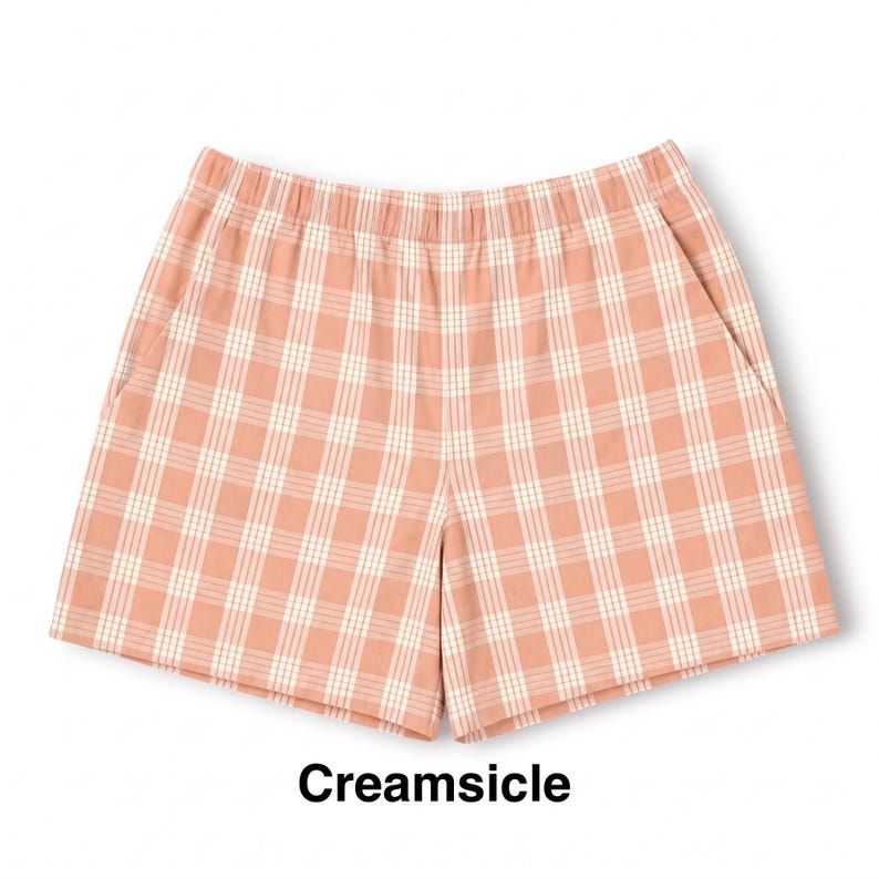 K&ouml;nnte beinhalten: Eine Shorts mit pfirsichfarbenem und wei&szlig;em Karomuster, ausgestattet mit einem elastischen Bund und zwei Seitentaschen. Der Text Creamsicle ist in Schwarz unter dem Kleidungsst&uuml;ck aufgedruckt und gibt die Farbgebung des Karomusters an.