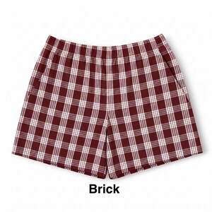 K&ouml;nnte beinhalten: Eine kurze Hose mit einem rot-wei&szlig;en Karomuster in Ziegelfarbe. Die Shorts verf&uuml;gen &uuml;ber einen elastischen Bund und zwei Seitentaschen. Das Wort Brick ist in schwarzer Schrift unter der Hose abgedruckt und bezeichnet die Farbe.
