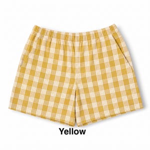 K&ouml;nnte beinhalten: Senfgelbe Shorts mit wei&szlig;em Karomuster. Die Shorts verf&uuml;gen &uuml;ber einen elastischen Bund, zwei Seitentaschen und einen geraden Schnitt. Das Wort Yellow ist in schwarzer Schrift unter dem Kleidungsst&uuml;ck auf wei&szlig;em Grund gedruckt.