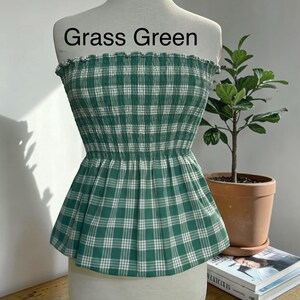 Peut inclure: Un haut bustier sans bretelles &agrave; motif &eacute;cossais vert gazon et blanc. Le v&ecirc;tement pr&eacute;sente un corsage smock&eacute; et &eacute;lastique avec un bord sup&eacute;rieur volant&eacute; et un ourlet &agrave; basque &eacute;vas&eacute;. Le texte "Grass Green" est imprim&eacute; au-dessus du v&ecirc;tement.