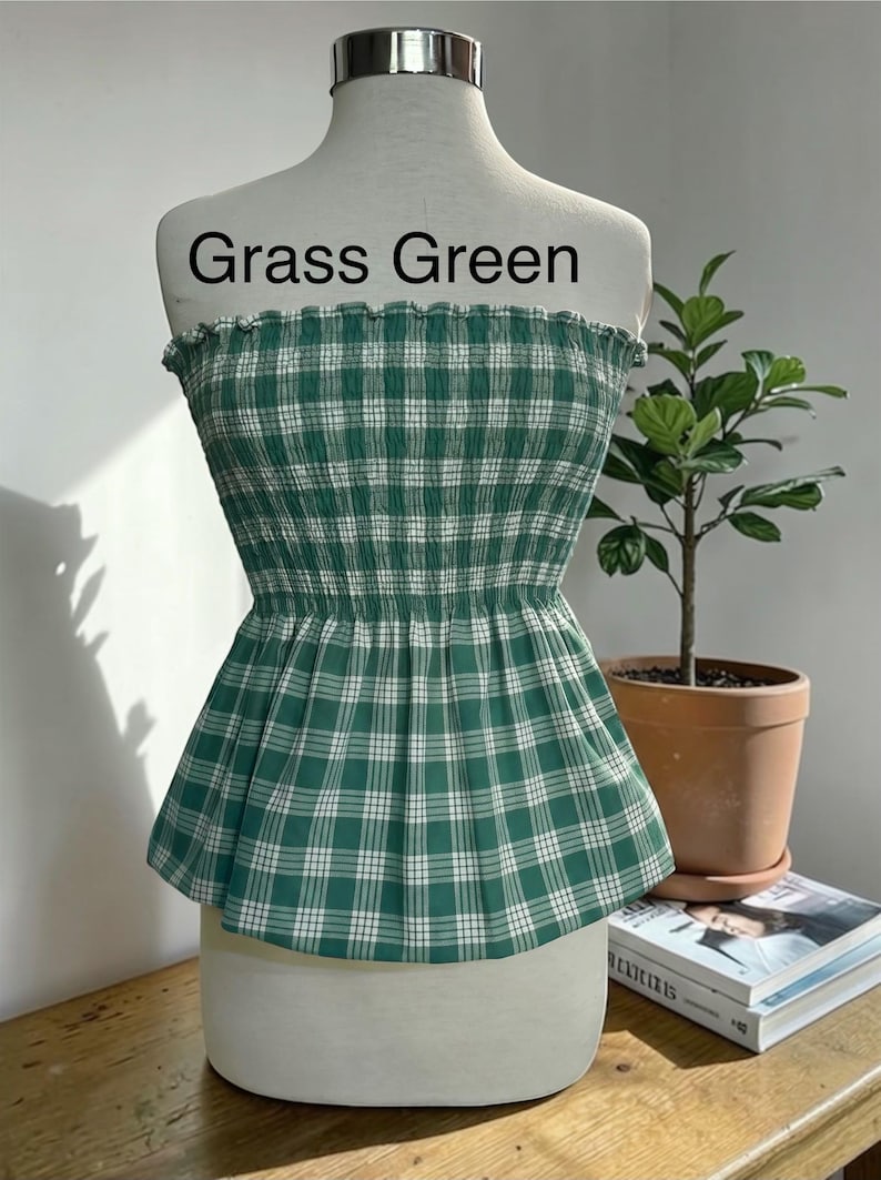 Peut inclure: Un haut bustier sans bretelles &agrave; motif &eacute;cossais vert gazon et blanc. Le v&ecirc;tement pr&eacute;sente un corsage smock&eacute; et &eacute;lastique avec un bord sup&eacute;rieur volant&eacute; et un ourlet &agrave; basque &eacute;vas&eacute;. Le texte "Grass Green" est imprim&eacute; au-dessus du v&ecirc;tement.