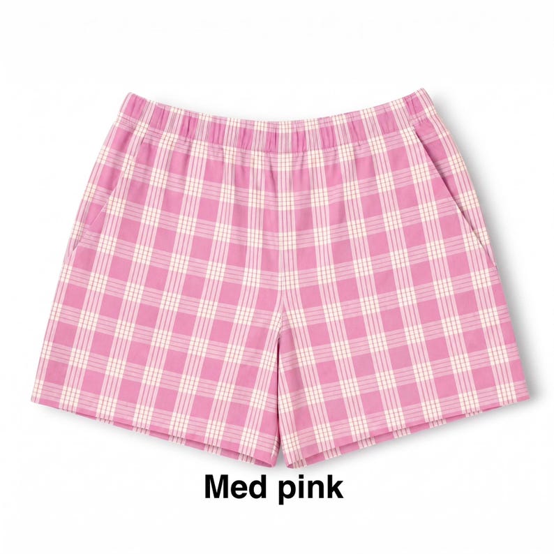 K&ouml;nnte beinhalten: Rosa-wei&szlig; karierte Shorts mit elastischem Bund und zwei Seitentaschen. Der Stoff zeigt ein durchgehendes Karomuster. Unter der Shorts ist der Text "Med pink" in schwarzer Schrift aufgedruckt.