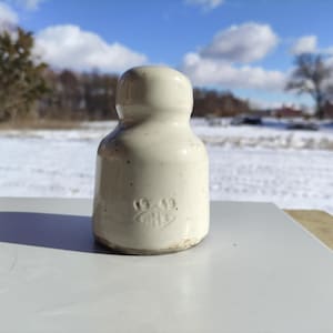 Könnte beinhalten: Weißer Keramik-Isolator mit der Nummer "1919" auf der Seite.