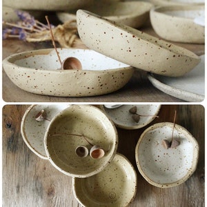 May include: Set of five small, speckled ceramic bowls with a white glaze. The bowls are arranged in a stack and are decorated with small brown specks. The bowls are perfect for serving snacks, dips, or sauces.