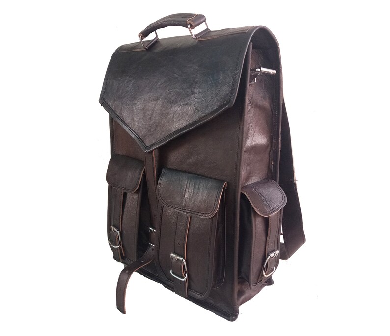 Pode incluir: Uma mochila de couro marrom com v&aacute;rios bolsos e fivelas. A mochila tem um fecho de aba e uma al&ccedil;a superior.