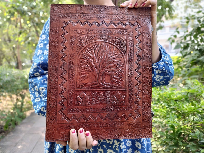 Puede incluir: Un diario de cuero marr&oacute;n con un dise&ntilde;o en relieve de un &aacute;rbol de la vida. El &aacute;rbol est&aacute; rodeado por un borde de nudo celta.