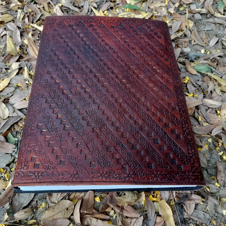 Pu&ograve; includere: Un diario in pelle marrone con un motivo in rilievo decorativo. Il diario ha una copertina marrone scuro con un motivo diagonale di piccoli quadrati e disegni floreali.