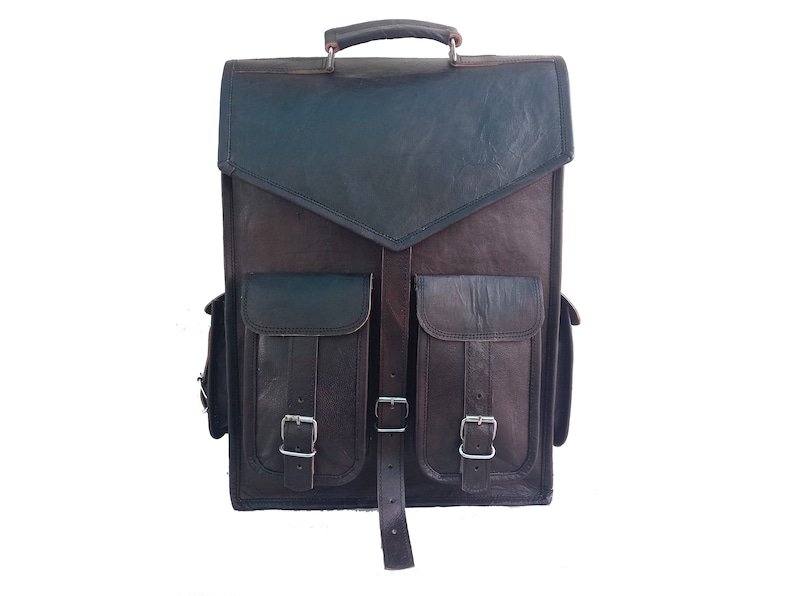 Pode incluir: Uma mochila de couro marrom com dois bolsos grandes na frente e uma al&ccedil;a superior. Os bolsos t&ecirc;m fivelas e al&ccedil;as.