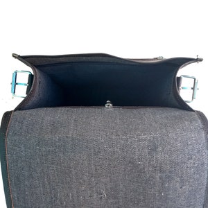 Pode incluir: Uma bolsa de mensageiro de lona preta com fecho de correr e aba. A bolsa est&aacute; aberta e o interior est&aacute; vazio.