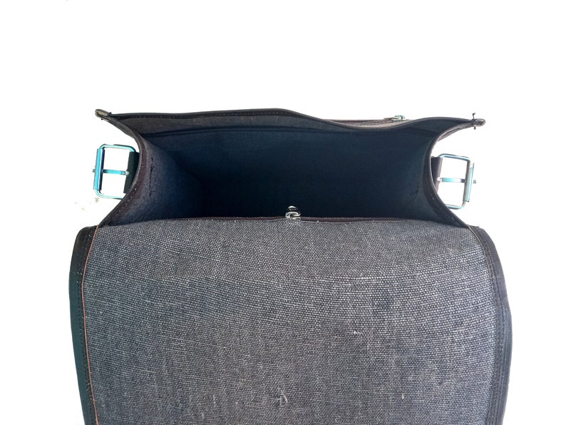 Pode incluir: Uma bolsa de mensageiro de lona preta com fecho de correr e aba. A bolsa est&aacute; aberta e o interior est&aacute; vazio.