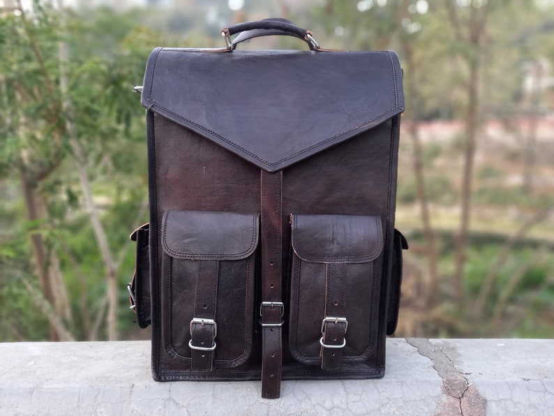 Pode incluir: Uma mochila de couro marrom com dois bolsos grandes na frente e um fecho de aba. A mochila tem uma al&ccedil;a superior e al&ccedil;as de ombro ajust&aacute;veis.