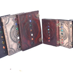 K&ouml;nnte beinhalten: Ein Set aus sechs ledergebundenen Tageb&uuml;chern mit dekorativen Pr&auml;gemustern und bunten Edelstein-Akzenten. Jedes Tagebuch hat eine einzigartige Farbe und ein einzigartiges Design.