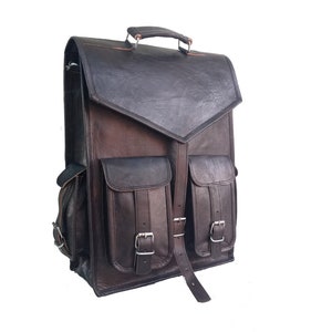 Pode incluir: Uma mochila de couro marrom com dois bolsos grandes na frente e um fecho de aba. A mochila tem uma al&ccedil;a superior e al&ccedil;as ajust&aacute;veis.